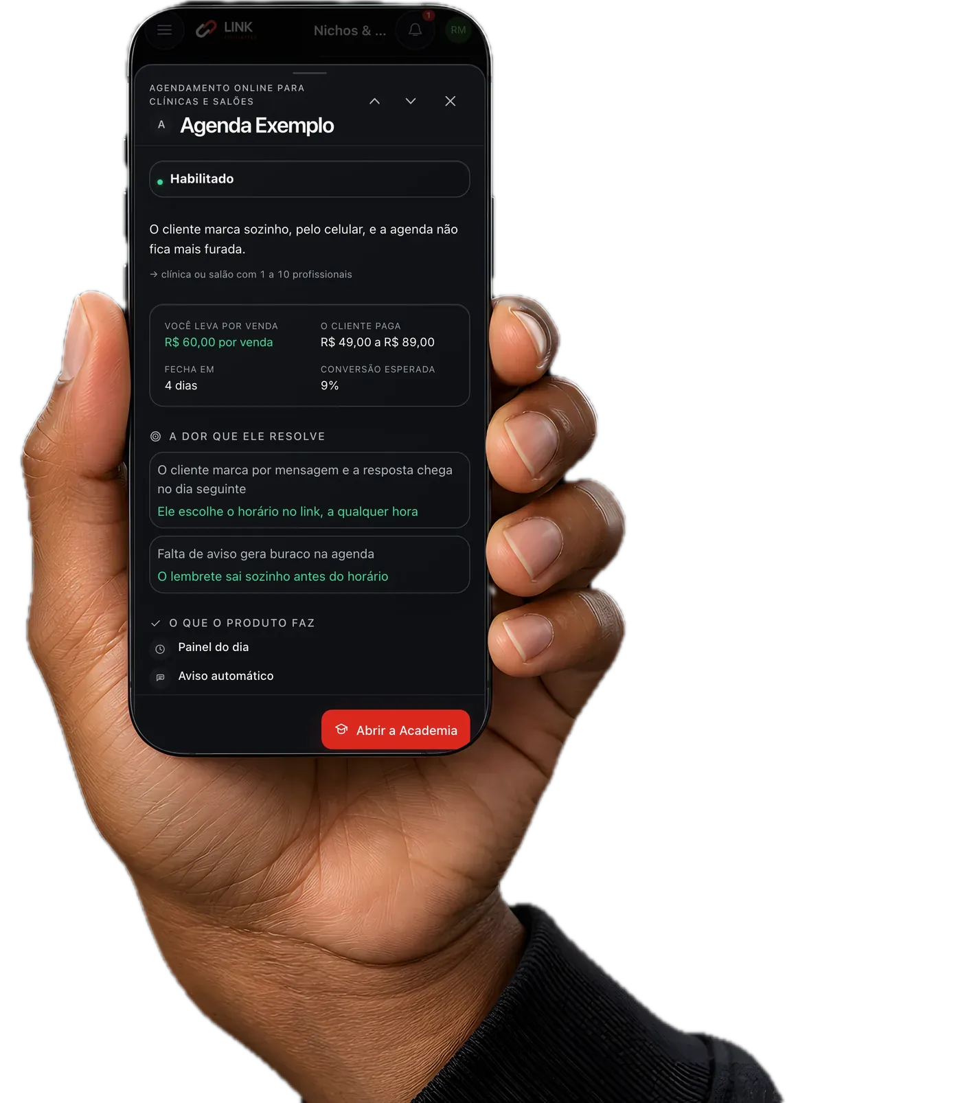 Mão segurando o celular com o briefing de um produto aberto no painel: quanto o parceiro leva por venda, o preço que o cliente paga e a conversão esperada, numa conta de demonstração